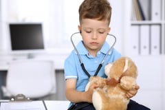 Doutor pequeno que examina um paciente ntoy do urso pelo estetoscópio imagens de stock Doutor pequeno que examina um paciente ntoy do urso pelo estetoscópio imagens de stock