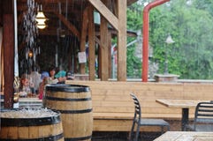 Downpour in the pub`s garden. Eger, Hungary - May 19, 2018: people sitting in the pub are watching the big rain falling outside Downpour in the pub`s garden. Eger, Hungary - May 19, 2018: people sitting in the pub are watching the big rain falling outside