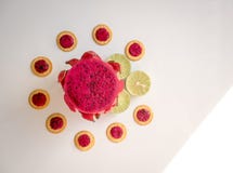 Drago rosso della frutta su un fondo bianco vicino a calce verde ed ai biscotti freschi Prima colazione tropicale Fotografie Stock Drago rosso della frutta su un fondo bianco vicino a calce verde ed ai biscotti freschi Prima colazione tropicale Fotografie Stock