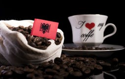 Drapeau albanais dans un sac avec des grains de café d'isolement sur le noir photographie stock Drapeau albanais dans un sac avec des grains de café d'isolement sur le noir photographie stock