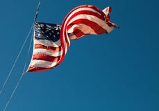 Drapeau américain soufflant dans le vent sur le ciel bleu Photo stock Drapeau américain soufflant dans le vent sur le ciel bleu Photo stock
