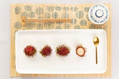Draufsicht einer Rambutanwüste mit Chinaware, goldenem Löffel und Essstäbchen lizenzfreie stockfotos Draufsicht einer Rambutanwüste mit Chinaware, goldenem Löffel und Essstäbchen lizenzfreie stockfotos