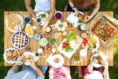 Draufsicht über die Leute, die das Mittagessen am Gartentisch während der Partei essen stockfotos Draufsicht über die Leute, die das Mittagessen am Gartentisch während der Partei essen stockfotos