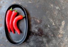 Drei ganze heiße rote Pfeffer auf einem schwarzen ovalen Behälter, gelassen von der Mitte, von oben lizenzfreie stockfotos Drei ganze heiße rote Pfeffer auf einem schwarzen ovalen Behälter, gelassen von der Mitte, von oben lizenzfreie stockfotos