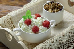 Drewniana taca z smakowitym śniadaniem: chałupa ser z świeżymi malinkami i granola obraz stock Drewniana taca z smakowitym śniadaniem: chałupa ser z świeżymi malinkami i granola obraz stock