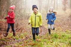 Drie Kinderen die de Winterbos doornemen stock foto Drie Kinderen die de Winterbos doornemen stock foto