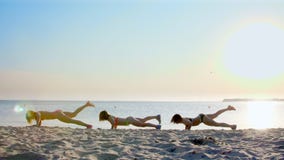 Drie mooie, atletische vrouwen, in zwempakken, die opdrukoefeningen doen, oefent synchroon uit Voor het strand, in de zomer, bij stock footage Drie mooie, atletische vrouwen, in zwempakken, die opdrukoefeningen doen, oefent synchroon uit Voor het strand, in de zomer, bij stock footage