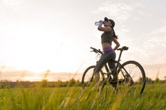 Drink water tijdens trainingen sporten vrouw op fietszonsondergang royalty-vrije stock foto Drink water tijdens trainingen sporten vrouw op fietszonsondergang royalty-vrije stock foto