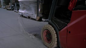 Driver del carrello elevatore che prende le scatole con mercanzie in grande magazzino Driver del carrello elevatore che prende le scatole con mercanzie in grande magazzino