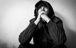 Drogue sans abri d'homme et intoxiqué d'alcool seul s'asseyant et déprimé sur la rue dans des vêtements d'hiver sentant froid et photos stock Drogue sans abri d'homme et intoxiqué d'alcool seul s'asseyant et déprimé sur la rue dans des vêtements d'hiver sentant froid et photos stock