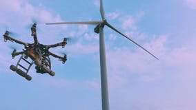 Drone takes off from the hands of a girl near a wind turbine, slow motion.