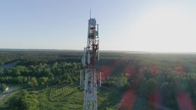 Drone view at telecommunication tower, worker servicing cellular antenna
