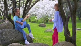 Duas amigas pequenas alegres que jogam a música na mola da guitarra no parque cena idílico bonita na natureza vídeos de arquivo Duas amigas pequenas alegres que jogam a música na mola da guitarra no parque cena idílico bonita na natureza vídeos de arquivo