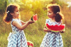 Duas irmãs mais nova engraçadas que comem a melancia fora no dia de verão morno e ensolarado Alimento biológico saudável para cri imagem de stock royalty free Duas irmãs mais nova engraçadas que comem a melancia fora no dia de verão morno e ensolarado Alimento biológico saudável para cri imagem de stock royalty free