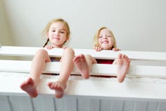 Duas irmãs mais nova que enganam ao redor, jogando e tendo o divertimento na cama de beliche gêmea imagens de stock Duas irmãs mais nova que enganam ao redor, jogando e tendo o divertimento na cama de beliche gêmea imagens de stock