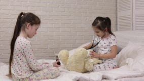 Duas meninas bonitos das crian?as que jogam o doutor com urso de peluche video estoque Duas meninas bonitos das crian?as que jogam o doutor com urso de peluche video estoque