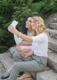 Duas meninas estão tomando selfies e estão comendo o gelado imagens de stock royalty free Duas meninas estão tomando selfies e estão comendo o gelado imagens de stock royalty free