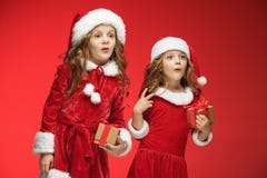 Duas meninas felizes em chapéus de Papai Noel com as caixas de presente no estúdio fotografia de stock royalty free Duas meninas felizes em chapéus de Papai Noel com as caixas de presente no estúdio fotografia de stock royalty free