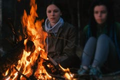 Duas mulheres olham o fogo em uma noite do verão Fim de semana do feriado da família imagem de stock Duas mulheres olham o fogo em uma noite do verão Fim de semana do feriado da família imagem de stock