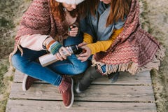 Duas mulheres que sentam na parte do prado um o copo do caldo imagem de stock Duas mulheres que sentam na parte do prado um o copo do caldo imagem de stock