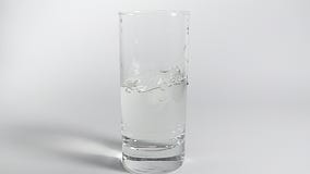 Duas partes de gelo que caem no vidro transparente da água clara um após o outro Movimento lento no fundo branco com sombra vídeos de arquivo Duas partes de gelo que caem no vidro transparente da água clara um após o outro Movimento lento no fundo branco com sombra vídeos de arquivo
