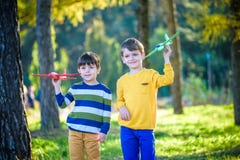 Due bambini felici del fratello che giocano con l'aeroplano del giocattolo contro il fondo blu del cielo di estate Aereo della sc fotografia stock libera da diritti Due bambini felici del fratello che giocano con l'aeroplano del giocattolo contro il fondo blu del cielo di estate Aereo della sc fotografia stock libera da diritti