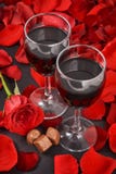 Due bicchieri di vino, rosa, petali e cioccolato su un fondo nero immagini stock Due bicchieri di vino, rosa, petali e cioccolato su un fondo nero immagini stock