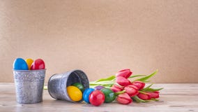 Due calici d'argento con le uova di Pasqua variopinte ed i tulipani rossi immagine stock Due calici d'argento con le uova di Pasqua variopinte ed i tulipani rossi immagine stock