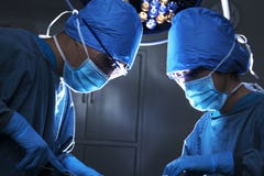 Due chirurghi che guardano giù, lavoranti e concentrantesi al tavolo operatorio fotografie stock libere da diritti Due chirurghi che guardano giù, lavoranti e concentrantesi al tavolo operatorio fotografie stock libere da diritti