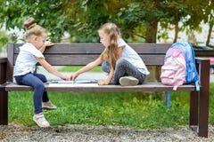 Due compagni di classe delle amiche assorbono il parco della scuola Il concetto di scuola, amicizia, disegno, studio, hobby immagine stock libera da diritti Due compagni di classe delle amiche assorbono il parco della scuola Il concetto di scuola, amicizia, disegno, studio, hobby immagine stock libera da diritti