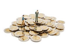 Due genti miniatura che camminano e che stanno sul mucchio di nuove 10 monete di baht tailandese fotografia stock libera da diritti Due genti miniatura che camminano e che stanno sul mucchio di nuove 10 monete di baht tailandese fotografia stock libera da diritti