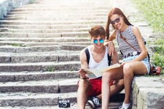 Due giovani turisti che si rilassano e che esaminano una mappa della guida fotografia stock Due giovani turisti che si rilassano e che esaminano una mappa della guida fotografia stock