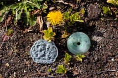 Due pietre della giada scolpite con le forme orientali su terra e su vegetazione fotografie stock Due pietre della giada scolpite con le forme orientali su terra e su vegetazione fotografie stock