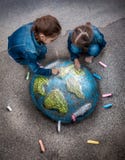 Due ragazze che disegnano immagine realistica della terra con i gessi su terra fotografia stock Due ragazze che disegnano immagine realistica della terra con i gessi su terra fotografia stock