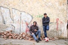 Due teppisti della via che stanno contro un dolore dei graffiti fotografia stock Due teppisti della via che stanno contro un dolore dei graffiti fotografia stock