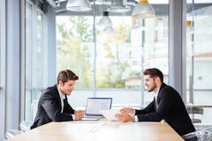 Due uomini d'affari felici che lavorano insieme facendo uso del computer portatile sulla riunione d'affari immagini stock libere da diritti Due uomini d'affari felici che lavorano insieme facendo uso del computer portatile sulla riunione d'affari immagini stock libere da diritti
