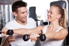 Dumbbells de levantamento da mulher quando ajuda do instrutor fotografia de stock Dumbbells de levantamento da mulher quando ajuda do instrutor fotografia de stock