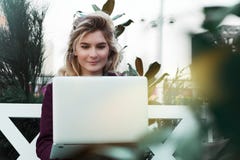Durchdachte junge Frau in den Gl?sern unter Verwendung eines Computers, sitzend auf einer Bank in einem Stadtpark Das Konzept der lizenzfreies stockbild Durchdachte junge Frau in den Gl?sern unter Verwendung eines Computers, sitzend auf einer Bank in einem Stadtpark Das Konzept der lizenzfreies stockbild