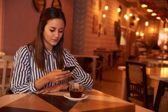 Durchdachtes millenial im Restaurant mit Telefon lizenzfreies stockfoto Durchdachtes millenial im Restaurant mit Telefon lizenzfreies stockfoto