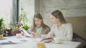 Dwa bizneswomanu dyskutuje prac spojrzenia i zagadnienia przez dokument?w w kawiarni zbiory Dwa bizneswomanu dyskutuje prac spojrzenia i zagadnienia przez dokument?w w kawiarni zbiory