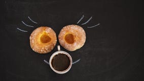 Dwa donuts z morelowym dżemu kłamstwem i filiżanka kawy na czarnej desce obrazy stock Dwa donuts z morelowym dżemu kłamstwem i filiżanka kawy na czarnej desce obrazy stock