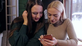 Dwa dziewczyny siedzą w kawiarni z telefonami zdjęcie wideo Dwa dziewczyny siedzą w kawiarni z telefonami zdjęcie wideo