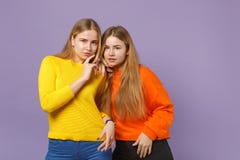 Dwa powabnej młodej blondynka bliźniaków siostr dziewczyny stoi w żywych kolorowych ubraniach, przyglądająca kamera na pastelu obrazy stock Dwa powabnej młodej blondynka bliźniaków siostr dziewczyny stoi w żywych kolorowych ubraniach, przyglądająca kamera na pastelu obrazy stock