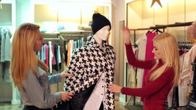 Dwa szczęśliwej dziewczyny patrzeje odziewają na mannequin w sklepie odzieżowym na zakupy zdjęcie wideo Dwa szczęśliwej dziewczyny patrzeje odziewają na mannequin w sklepie odzieżowym na zakupy zdjęcie wideo
