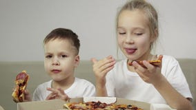 Dwa uroczy, śmieszni dzieciaki je pizzę _The chłopiec uśmiechać się, the dziewczyna śmiać się i pokazywać jej palec jak Pojęcie: zdjęcie wideo Dwa uroczy, śmieszni dzieciaki je pizzę _The chłopiec uśmiechać się, the dziewczyna śmiać się i pokazywać jej palec jak Pojęcie: zdjęcie wideo