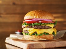 Dwoisty cheeseburger z sałatą, pomidorem, cebulą i topiącym amerykańskim serem, obraz stock Dwoisty cheeseburger z sałatą, pomidorem, cebulą i topiącym amerykańskim serem, obraz stock