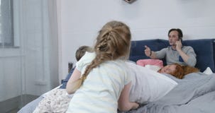 Dzieci ma poduszki walkę na rodzica łóżku, szczęśliwa rodzinna zabawa w sypialni zbiory wideo Dzieci ma poduszki walkę na rodzica łóżku, szczęśliwa rodzinna zabawa w sypialni zbiory wideo