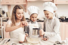 Dzieci z matką w kuchni Matka jest sumującym mąką, brat odsiewa je fotografia royalty free Dzieci z matką w kuchni Matka jest sumującym mąką, brat odsiewa je fotografia royalty free