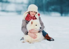 Dziecko ściska białego Samoyed psa w zima dniu fotografia royalty free Dziecko ściska białego Samoyed psa w zima dniu fotografia royalty free