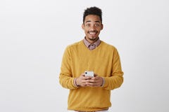 Dzielić wielką wiadomość z przyjacielem Portret szczęśliwy wstrząśnięty ciemnoskóry mężczyzna w modnym stroju, trzymający smartph obrazy royalty free Dzielić wielką wiadomość z przyjacielem Portret szczęśliwy wstrząśnięty ciemnoskóry mężczyzna w modnym stroju, trzymający smartph obrazy royalty free